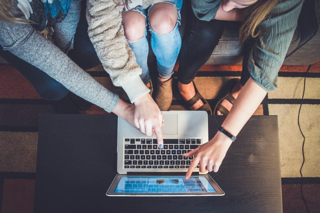 Group of women pointing to a computer screen figuring out blogging tips | North Branch Copywriting Co.  