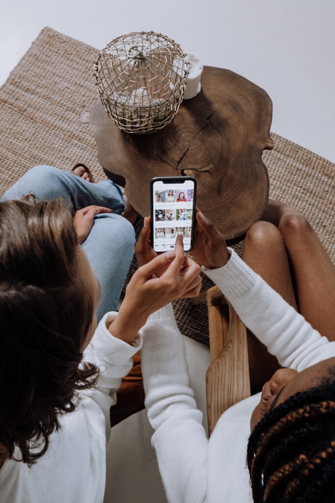 Two woman pointing to the phone screen and engaging with content repurposed for social media | North Branch Copywriting Co. 